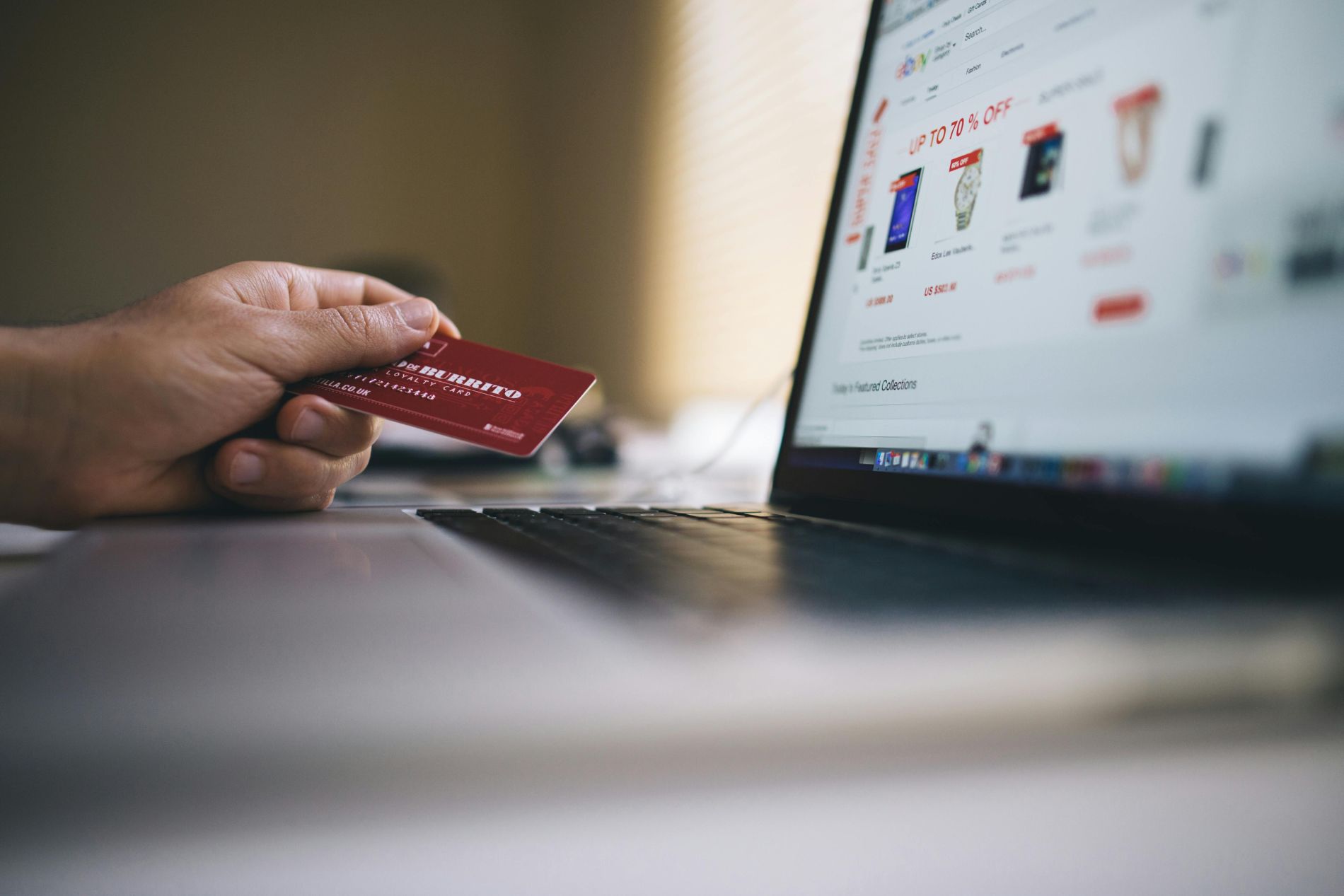 Slide of a hand holding a credit card in front of a laptop screen accessing an e-commerce website